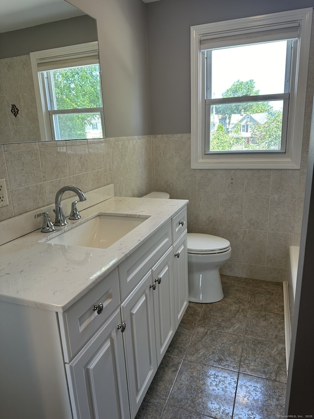 bathroom with vanity, toilet, and tile walls