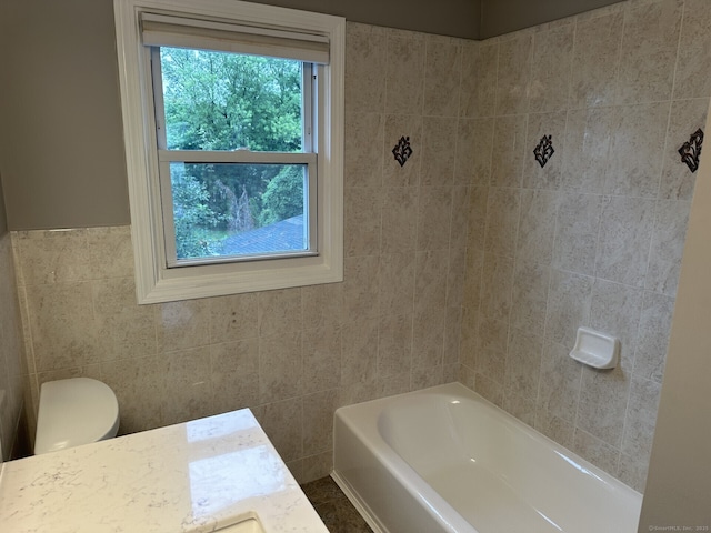 bathroom featuring vanity, toilet, tile walls, and a washtub