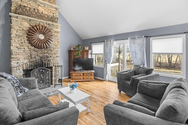 living room with a fireplace, high vaulted ceiling, and light wood-type flooring