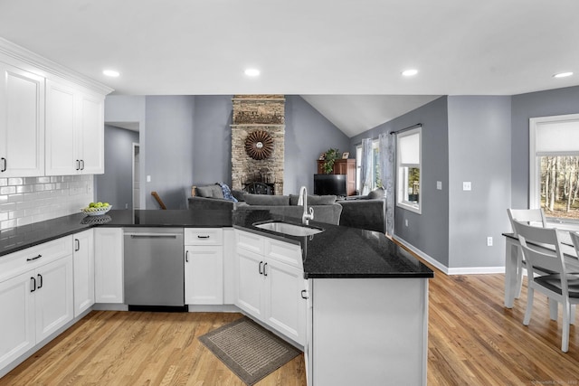 kitchen with stainless steel dishwasher, kitchen peninsula, sink, and white cabinets