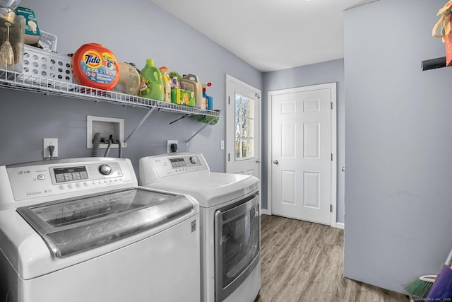 laundry area with washing machine and clothes dryer and light hardwood / wood-style flooring