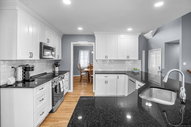 kitchen with white cabinetry, sink, stainless steel appliances, and dark stone countertops