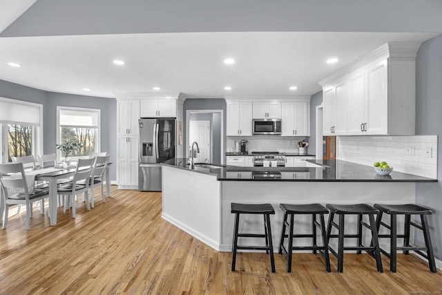 kitchen featuring appliances with stainless steel finishes, a breakfast bar, white cabinets, and kitchen peninsula