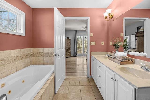 bathroom featuring tile patterned floors, vanity, ceiling fan with notable chandelier, and tiled tub