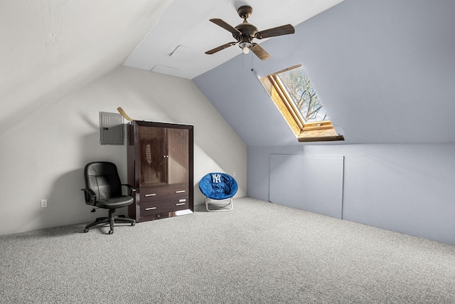 carpeted office featuring lofted ceiling with skylight and ceiling fan