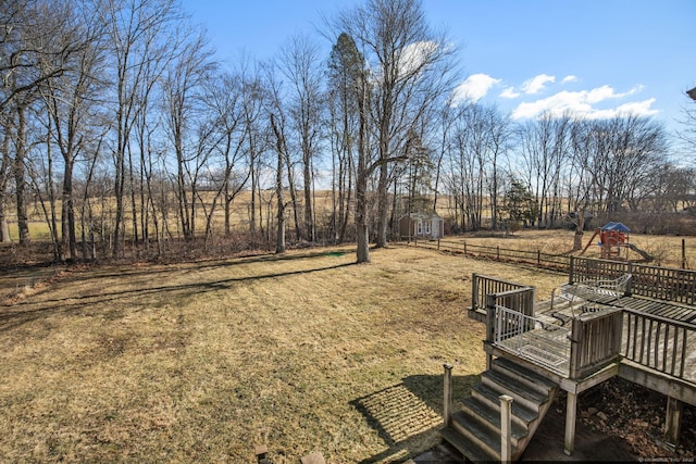 view of yard featuring a storage unit, a playground, and a deck