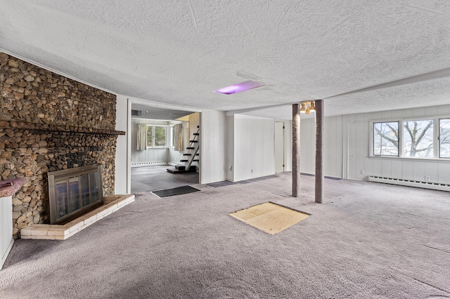 basement with a large fireplace, carpet floors, a textured ceiling, and a baseboard heating unit