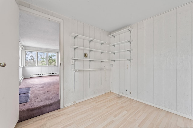 unfurnished room featuring baseboard heating and light hardwood / wood-style flooring