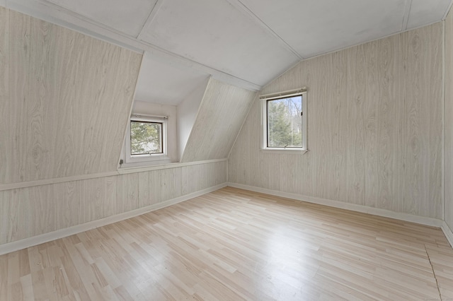 additional living space with lofted ceiling, a wealth of natural light, and light hardwood / wood-style floors