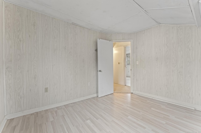 spare room with vaulted ceiling and light hardwood / wood-style flooring