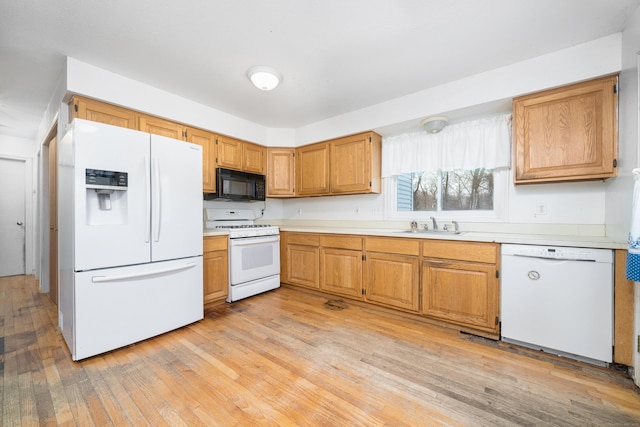 kitchen with sink, white appliances, and light hardwood / wood-style floors