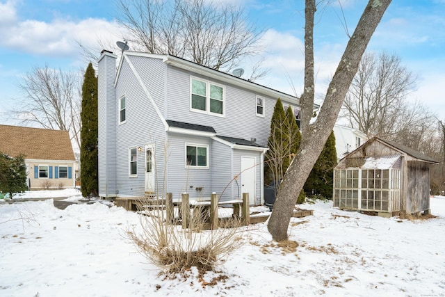 snow covered property featuring an outbuilding