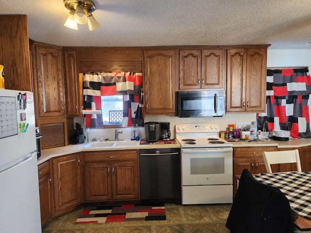 kitchen featuring sink, white appliances, a textured ceiling, and ceiling fan