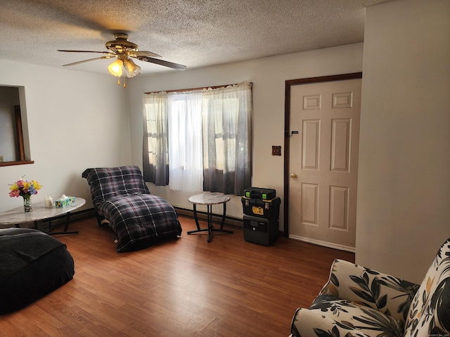 sitting room with ceiling fan, hardwood / wood-style floors, a textured ceiling, and baseboard heating