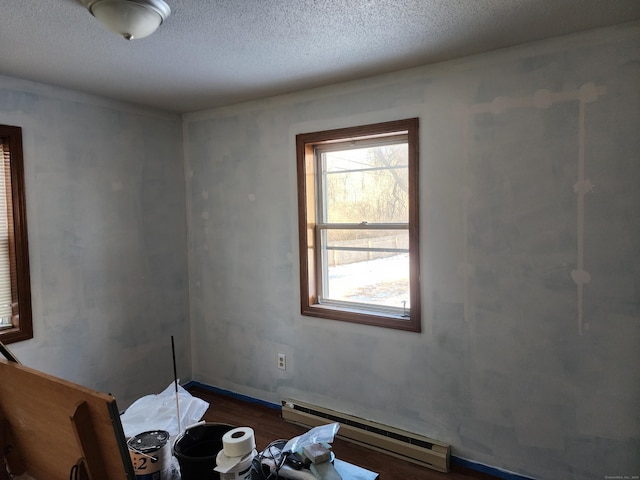 interior space with dark wood-type flooring, a baseboard radiator, and a textured ceiling