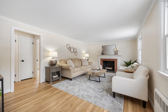 living room featuring light hardwood / wood-style floors, radiator heating unit, crown molding, and a fireplace