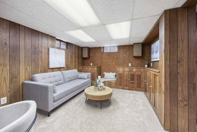 carpeted living room featuring wood walls and a paneled ceiling