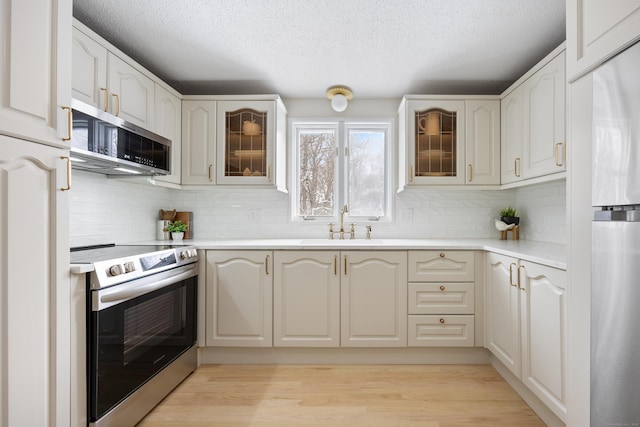 kitchen with sink, white cabinetry, light hardwood / wood-style flooring, and appliances with stainless steel finishes