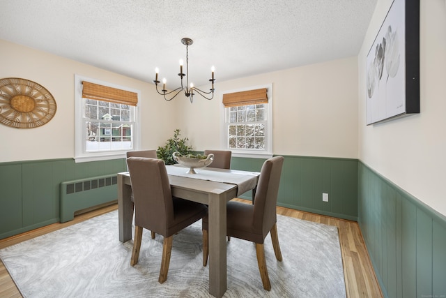 dining space with a textured ceiling, radiator, a chandelier, and light wood-type flooring