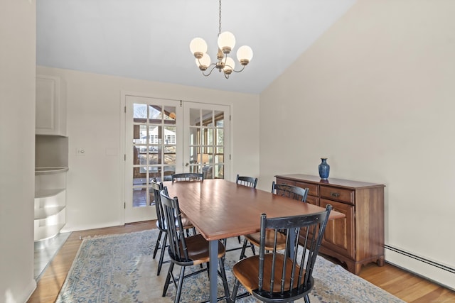 dining space featuring light hardwood / wood-style floors, a notable chandelier, baseboard heating, french doors, and vaulted ceiling