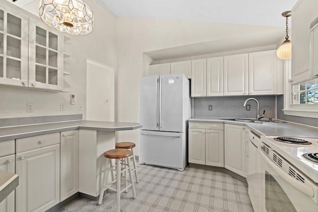 kitchen featuring white appliances, white cabinetry, sink, hanging light fixtures, and a breakfast bar