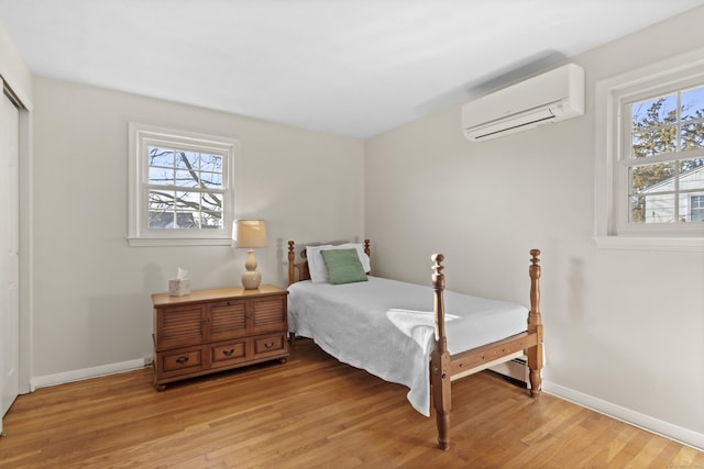 bedroom with an AC wall unit and light wood-type flooring