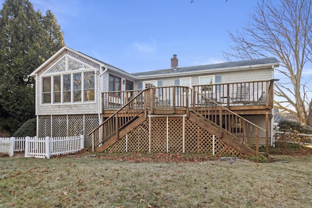 back of property featuring a deck, a sunroom, and a yard