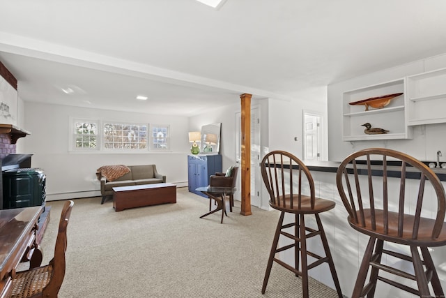 dining room featuring decorative columns, baseboard heating, and light carpet