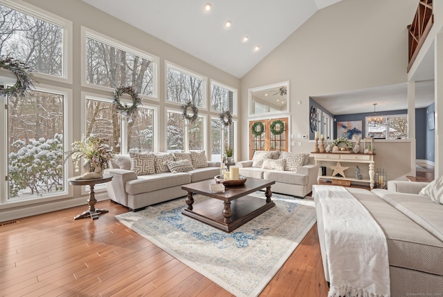 living room with high vaulted ceiling, hardwood / wood-style floors, and a notable chandelier