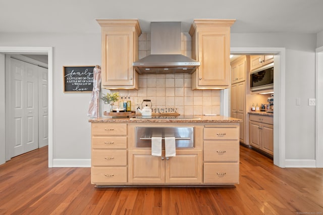 kitchen featuring light brown cabinetry, wall chimney range hood, and light wood-type flooring