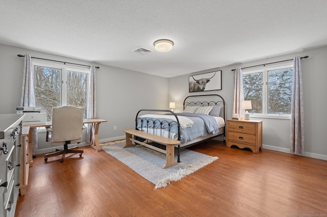 bedroom featuring a textured ceiling, multiple windows, and light wood-type flooring