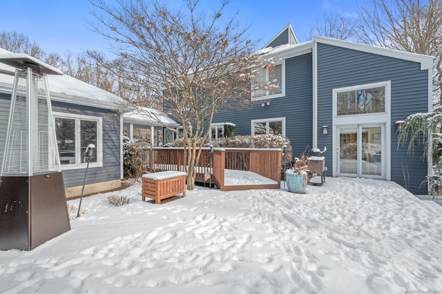 snow covered back of property with a wooden deck