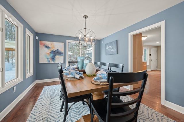 dining space featuring a healthy amount of sunlight, dark hardwood / wood-style flooring, and a chandelier