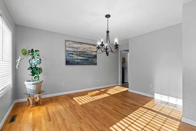 unfurnished room featuring wood-type flooring and a notable chandelier