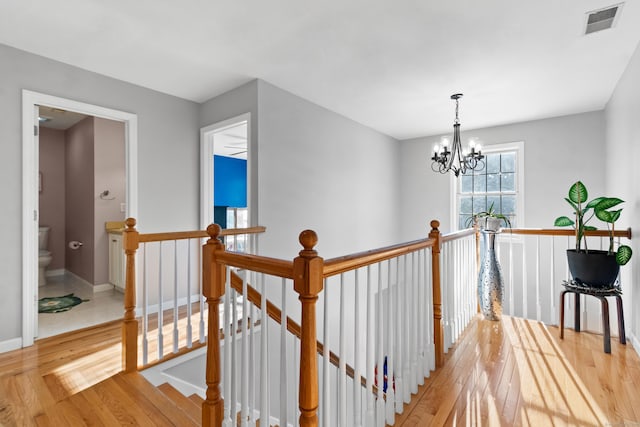 hall with light hardwood / wood-style floors and a notable chandelier