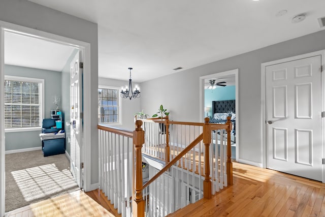 hallway featuring light hardwood / wood-style floors, a chandelier, and a healthy amount of sunlight