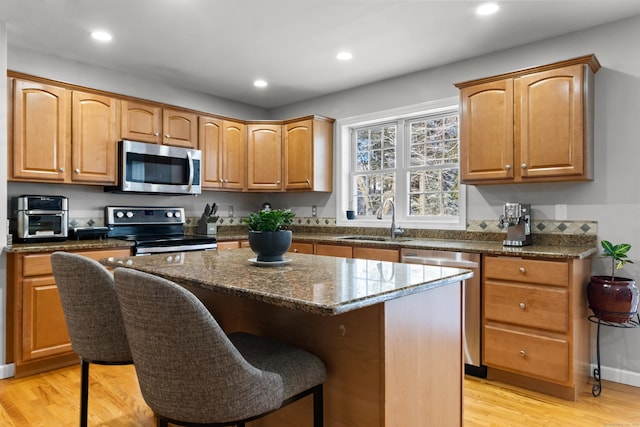 kitchen featuring light hardwood / wood-style floors, sink, appliances with stainless steel finishes, and a kitchen island