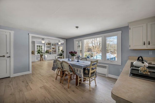 dining room featuring radiator heating unit, light wood-type flooring, and built in shelves