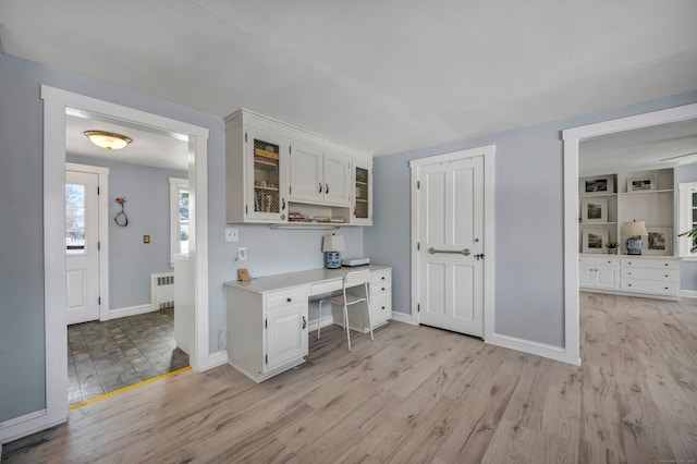 kitchen featuring radiator heating unit, light hardwood / wood-style floors, and white cabinets