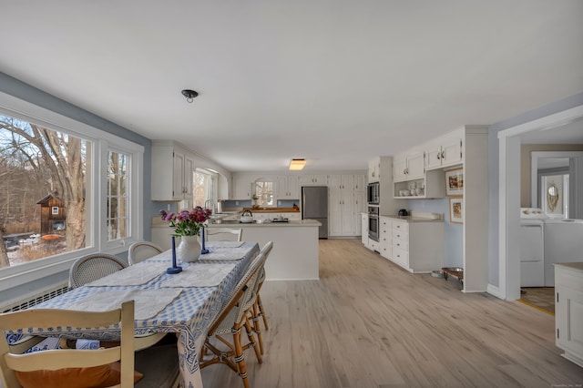 dining room featuring separate washer and dryer, a healthy amount of sunlight, and light wood-type flooring