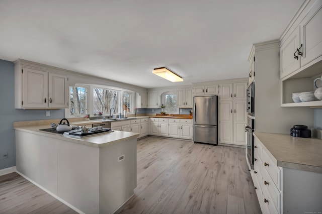 kitchen featuring stainless steel appliances, white cabinets, light hardwood / wood-style floors, and kitchen peninsula