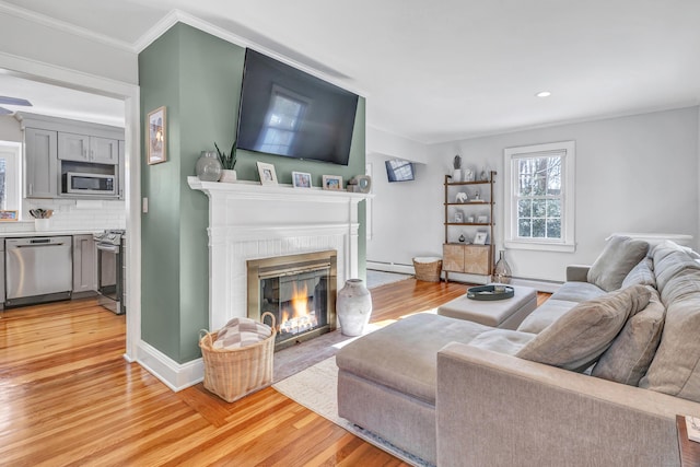 living room with crown molding, a fireplace, baseboard heating, and light hardwood / wood-style flooring