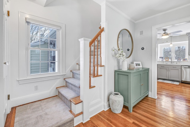 stairs with crown molding, ceiling fan, wood-type flooring, and a wealth of natural light