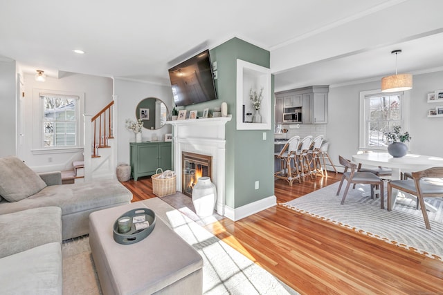 living room featuring ornamental molding, plenty of natural light, and light hardwood / wood-style flooring