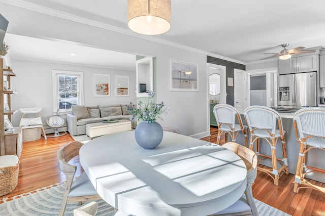 dining space featuring hardwood / wood-style flooring, ornamental molding, and ceiling fan