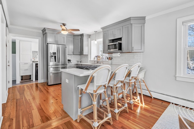 kitchen featuring pendant lighting, stainless steel appliances, kitchen peninsula, and gray cabinetry