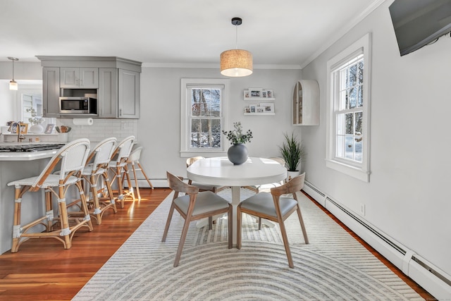 dining room with a baseboard radiator, ornamental molding, dark hardwood / wood-style flooring, and sink