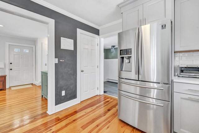 kitchen with decorative backsplash, light wood-type flooring, ornamental molding, and stainless steel refrigerator with ice dispenser