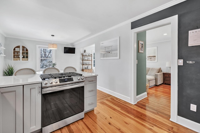 kitchen featuring gray cabinets, pendant lighting, ornamental molding, stainless steel gas range oven, and light wood-type flooring