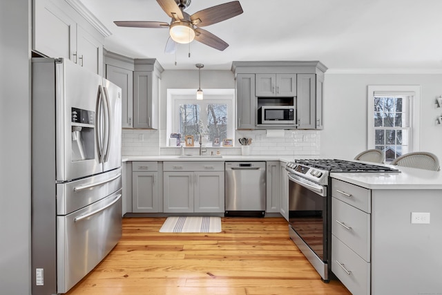 kitchen featuring stainless steel appliances, sink, gray cabinetry, and backsplash